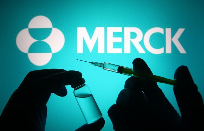 UKRAINE - 2021/04/27: In this photo illustration, silhouette of hands in medical gloves hold a medical syringe and a vial in front of Merck & Co pharmaceutical company logo. (Photo Illustration by Pavlo Gonchar/SOPA Images/LightRocket via Getty Images)